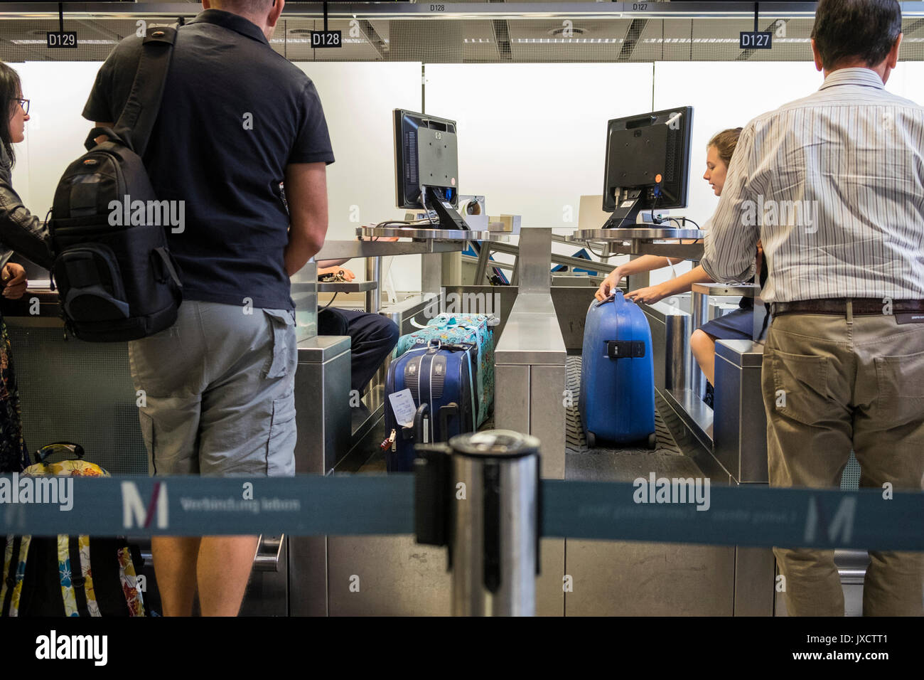 Checking in suitcases at check in desks in Munich airport, Bavaria, Germany Stock Photo