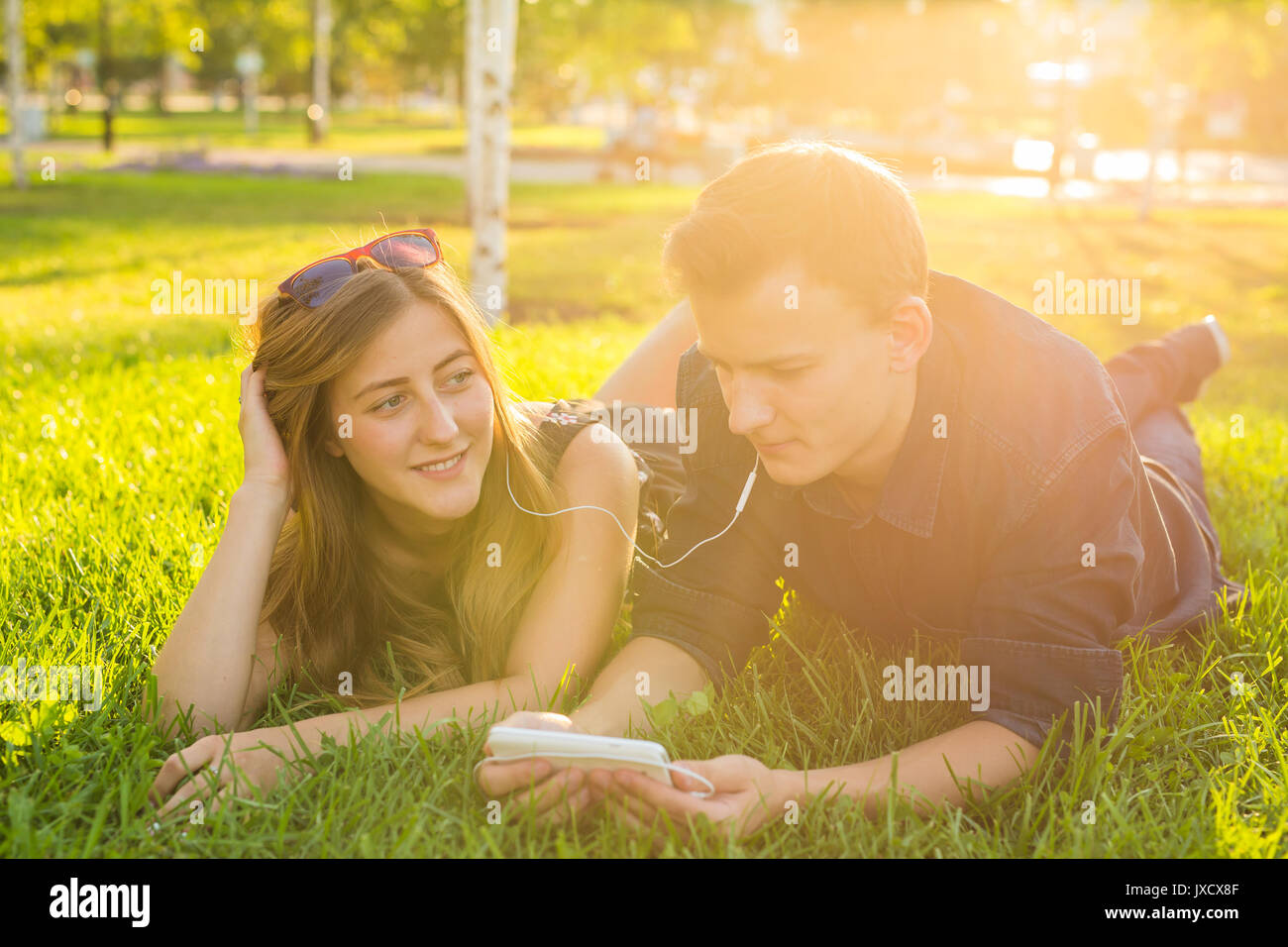 Young couple relax and listen to music on the grass in the park Stock ...