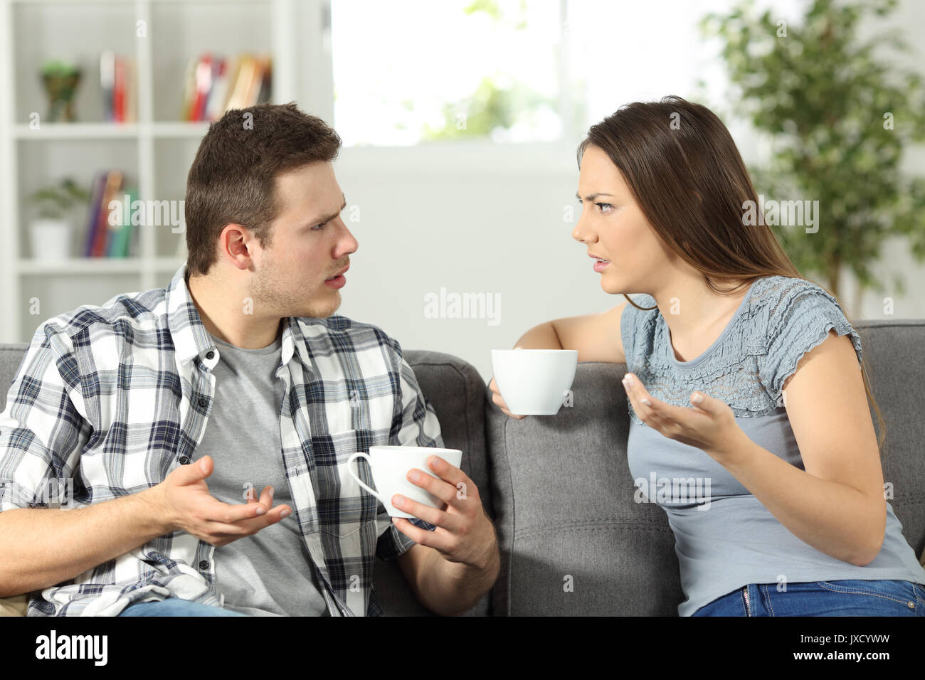 Angry couple arguing sitting on a couch at home Stock Photo