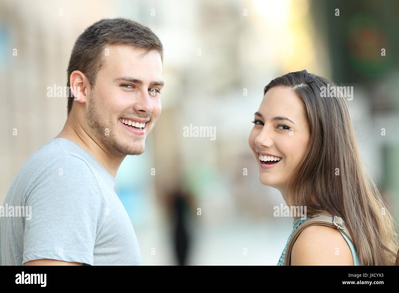 Portrait of a happy couple of teenagers looking at camera on the street Stock Photo