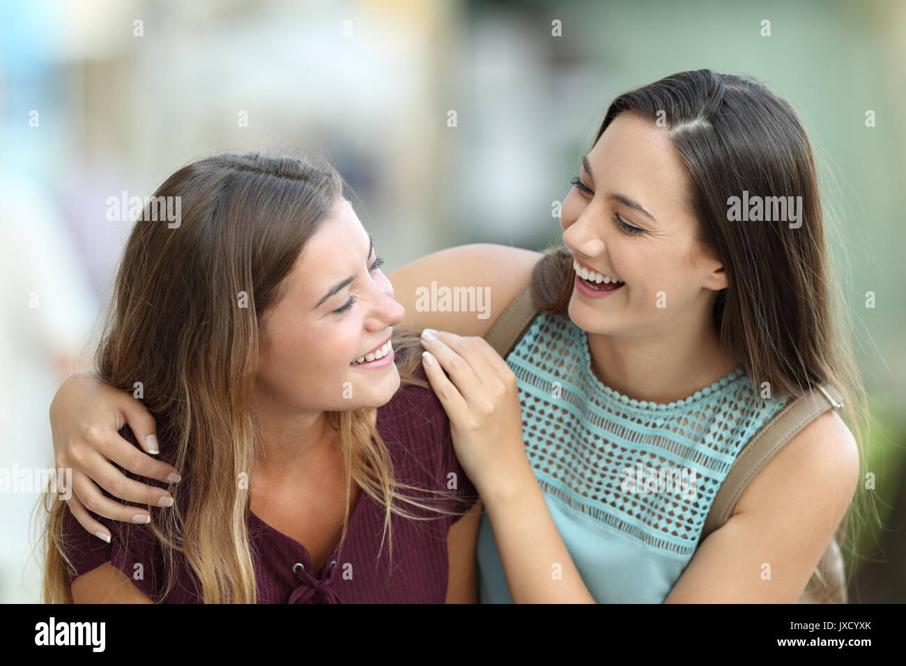 Portrait of two happy friends meeting and joking on the street Stock Photo