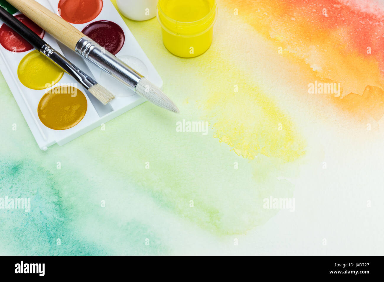watercolor palette with paintbrushes on multicolored hand painted background Stock Photo