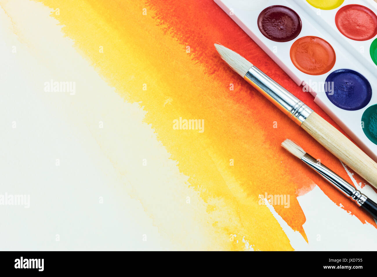 color palette with different brushes on bright red yellow watercolor background Stock Photo
