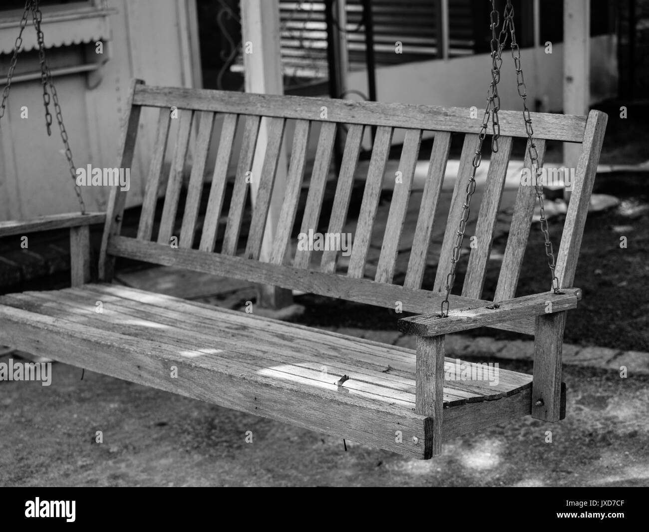 Black and white photo of an old wooden swing. Stock Photo