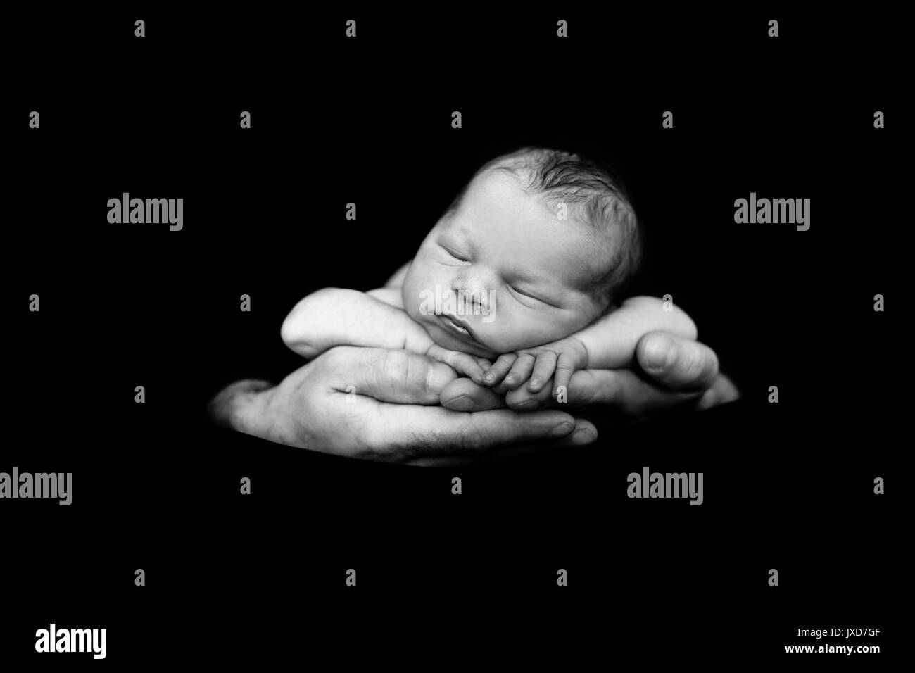 Beautiful baby boy, sleeping peacefully in fathers hands, infant sleeping, isolated image, black background, fathers love, tenderness, family concept Stock Photo