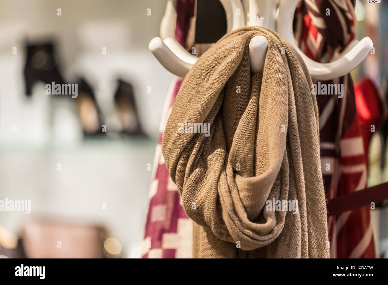 A brown scarf hanging on a white coat rack. This garment is useful in the winter or in case of severe cold. Stock Photo