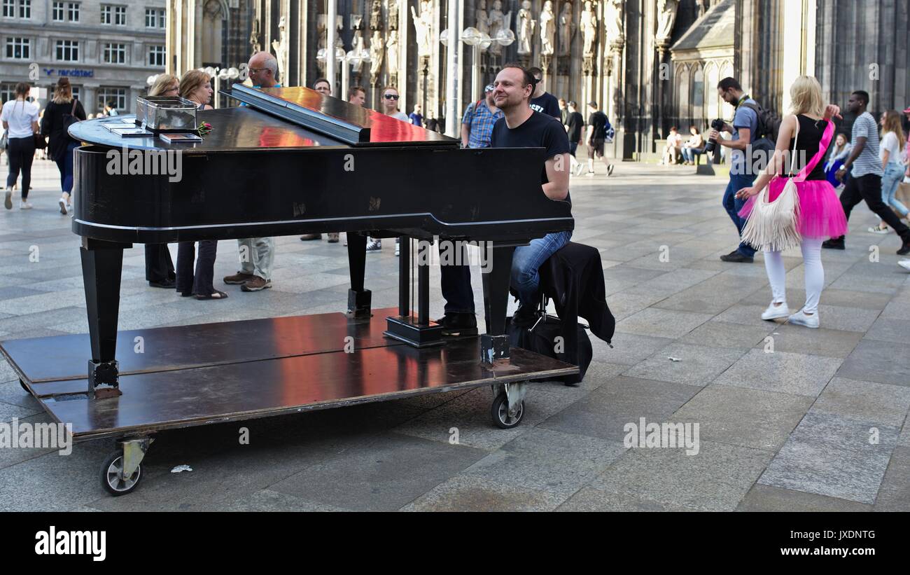 Man playing on grand piano in pedestrian zone in front of Cologne Cathedral main entrance Stock Photo
