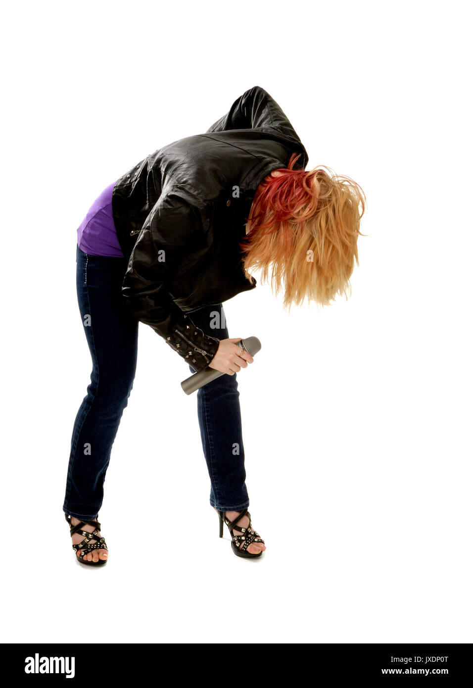 A Rocker Girl in Leather Jacket Doubles over Singing into Microphone Stock Photo