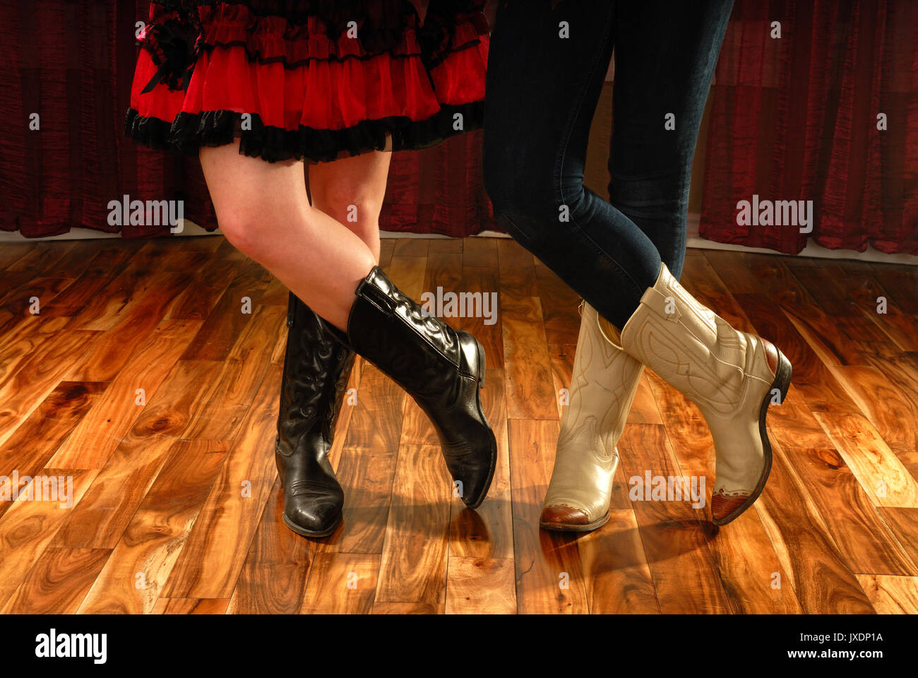 Female Legs in Cowboy Boots in a Line Dance Step on hardwood floor Stock Photo