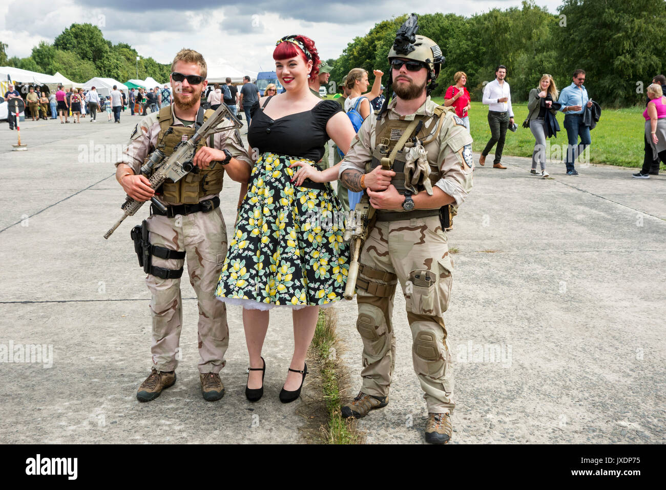 Re-enactors dressed as modern soldiers in 21th century military uniforms posing with woman in dress of the forties during militaria fair Stock Photo