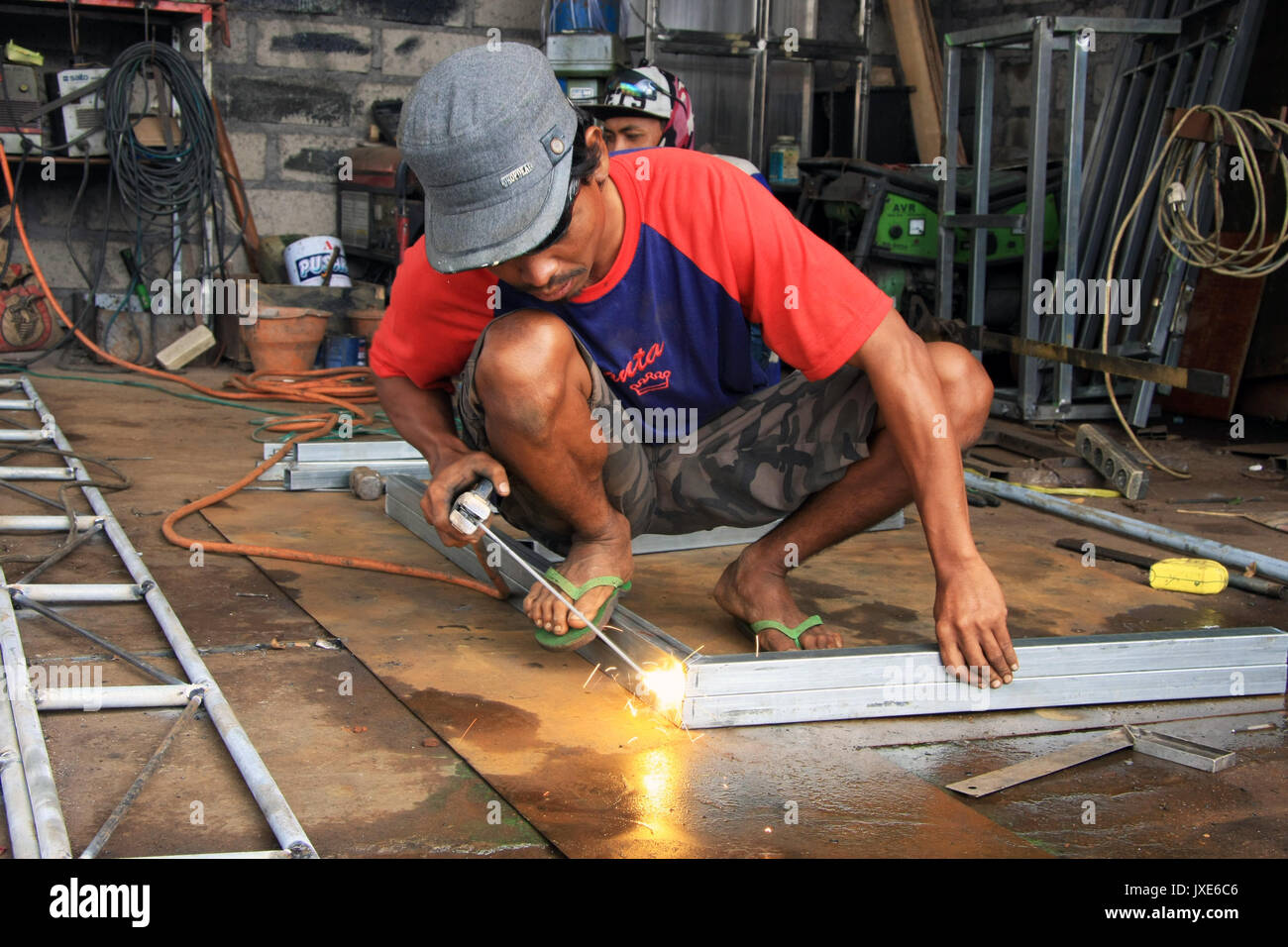 Kuta/Bali - September 13, 2016: Male welder/fabricator welding metalwork in workshop Stock Photo