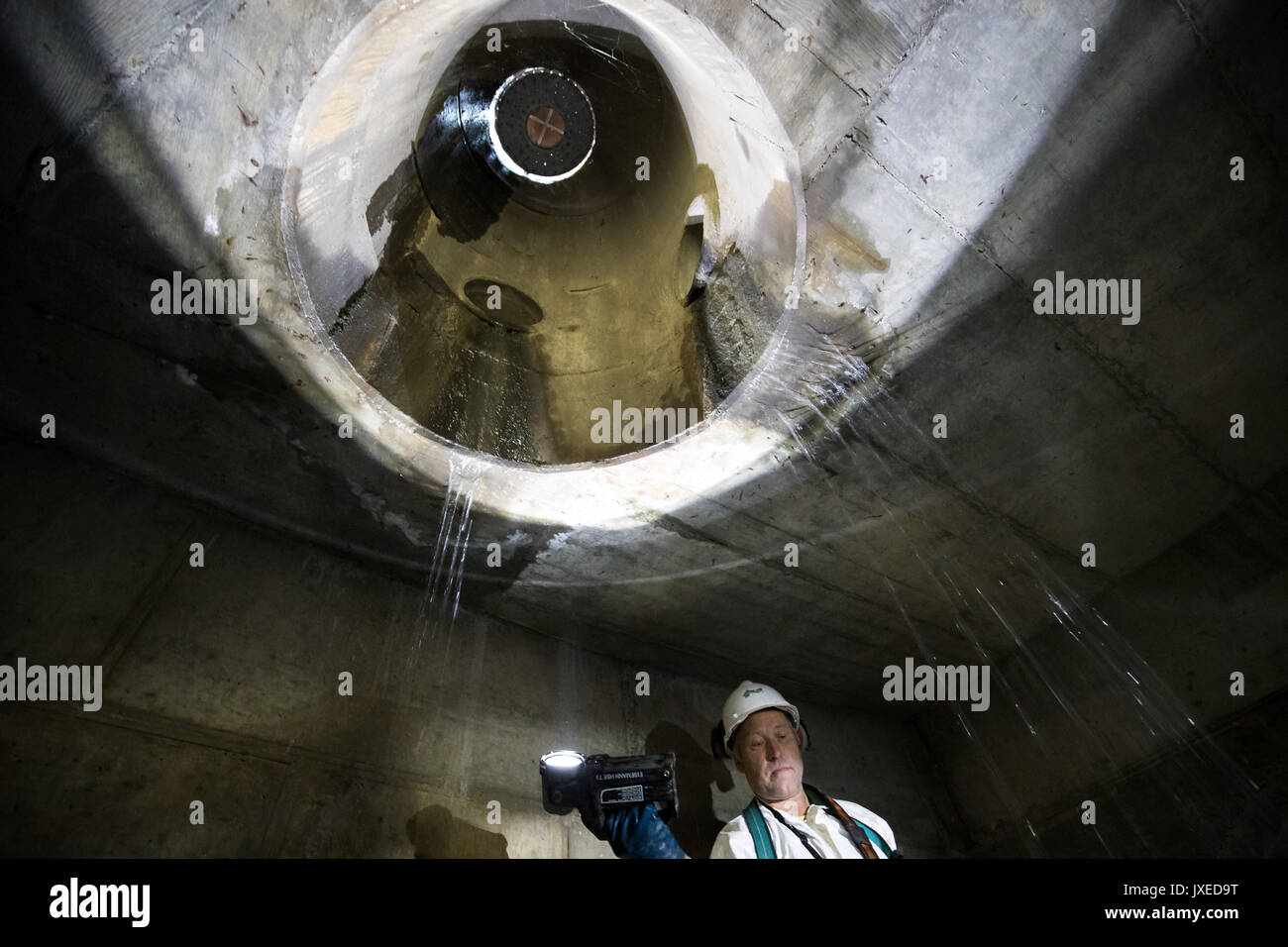 Schweinfurt, Germany. 17th July, 2017. The sewage worker Erwin Wolf lights the underground sewage during an inspeaction walk in Schweinfurt, Germany, 17 July 2017. The sewer in the middle reaches up to a street's drain cover. Unnoticed by many people sewage workers take care that cities do not turn into stinking cesspools. A great amount of the daytime they, therefore, spend in the underground. Photo: Daniel Karmann/dpa/Alamy Live News Stock Photo