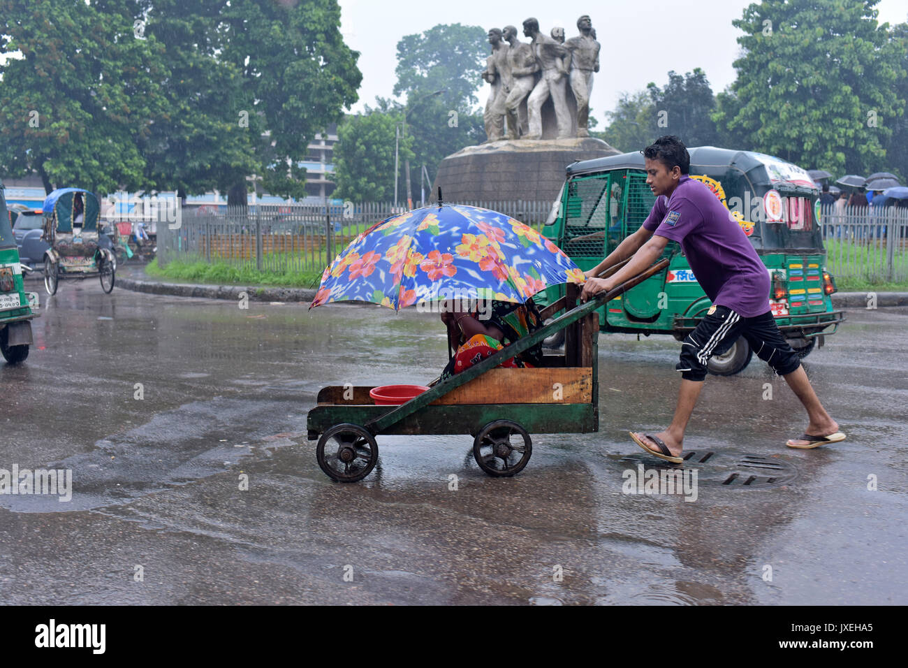 Dhaka, Bangladesh. 16th Aug, 2017.  A Bangladeshi man pushes cart of a disabled beggar during monsoon rain in Dhaka, Bangladesh. Credit: SK Hasan Ali/Alamy Live News Stock Photo