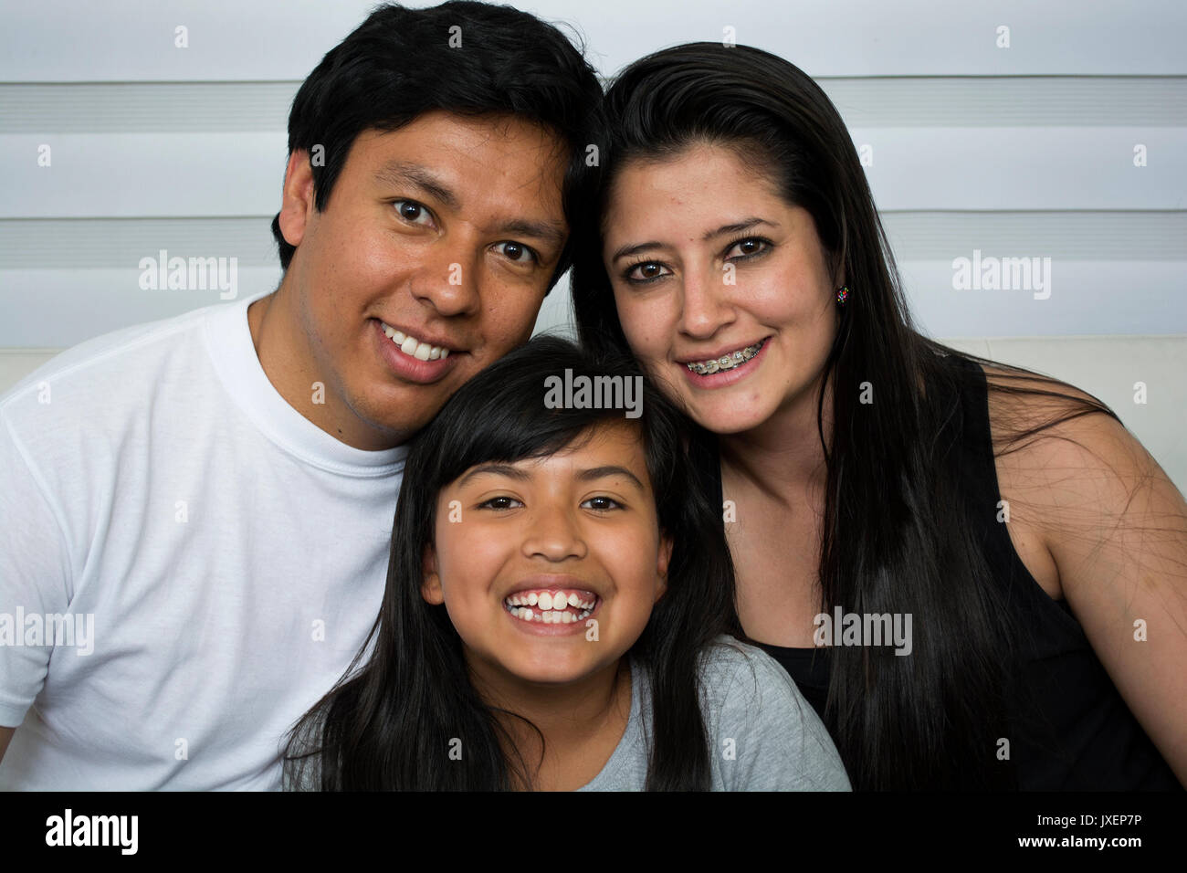 Happy young family sitting on sofa. Stock Photo
