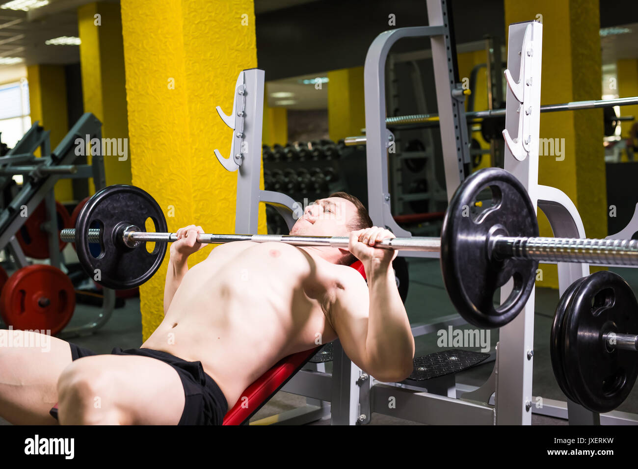 Weightlifter at the bench press lifting a barbell on an incline bench ...