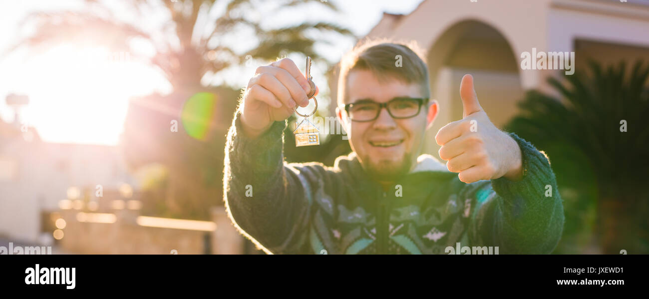 Happy young man showing off the key to his new home. Owner, real estate ...