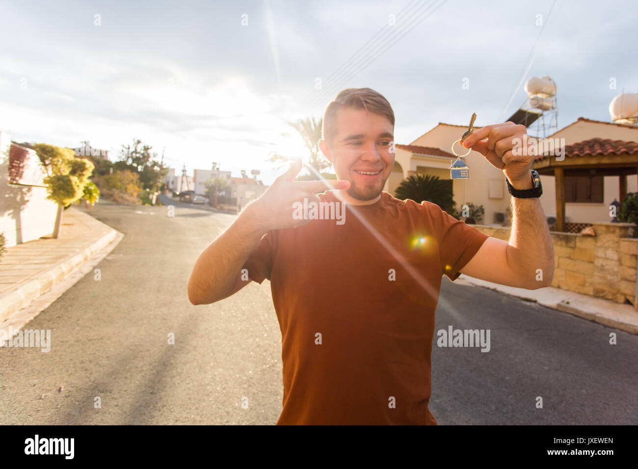Happy young man showing off the key to his new home. Owner, real estate ...