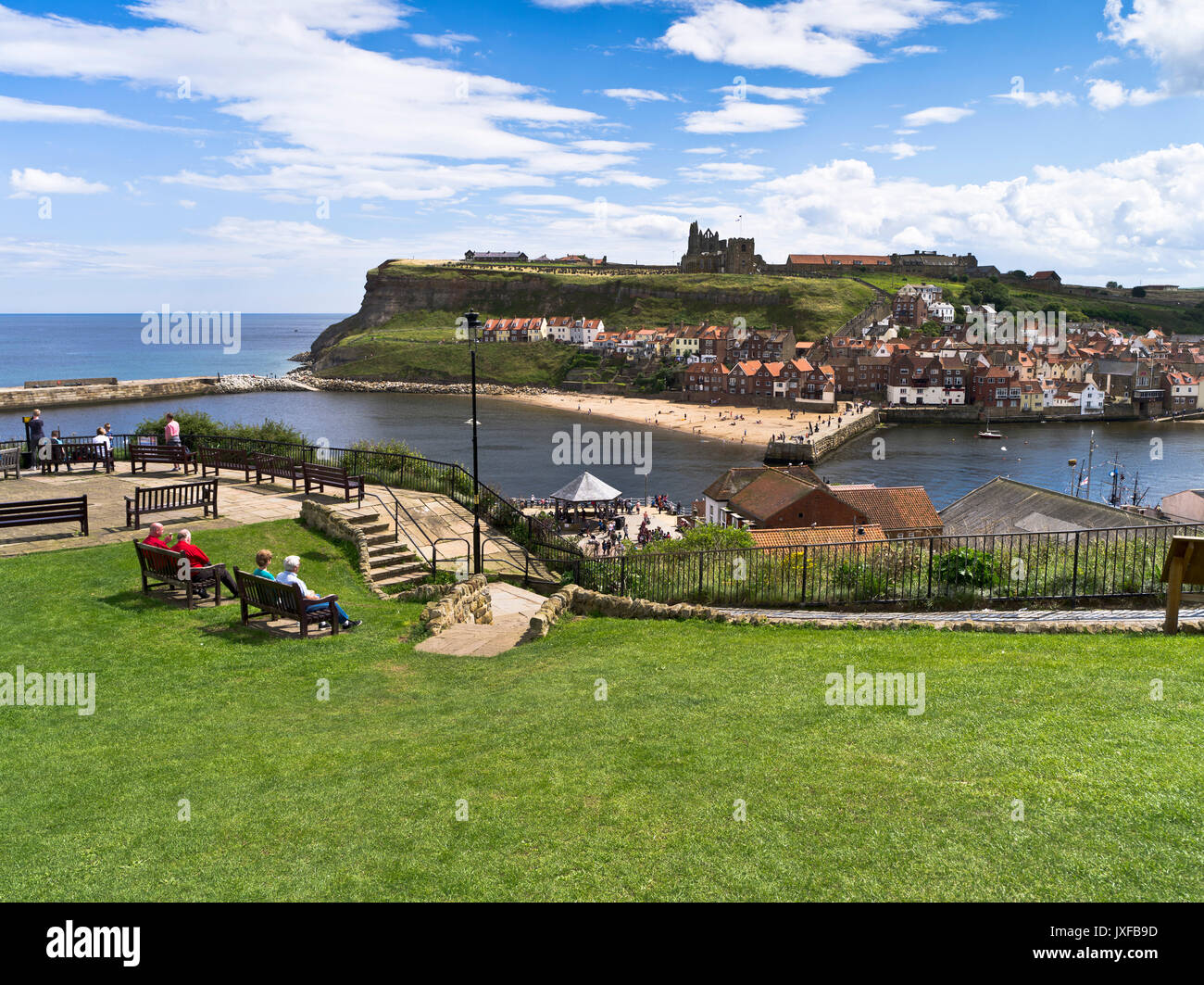 dh West Cliff town abbey coast WHITBY NORTH YORKSHIRE People couples sitting relaxing England tourists summers day tourism harbour Stock Photo