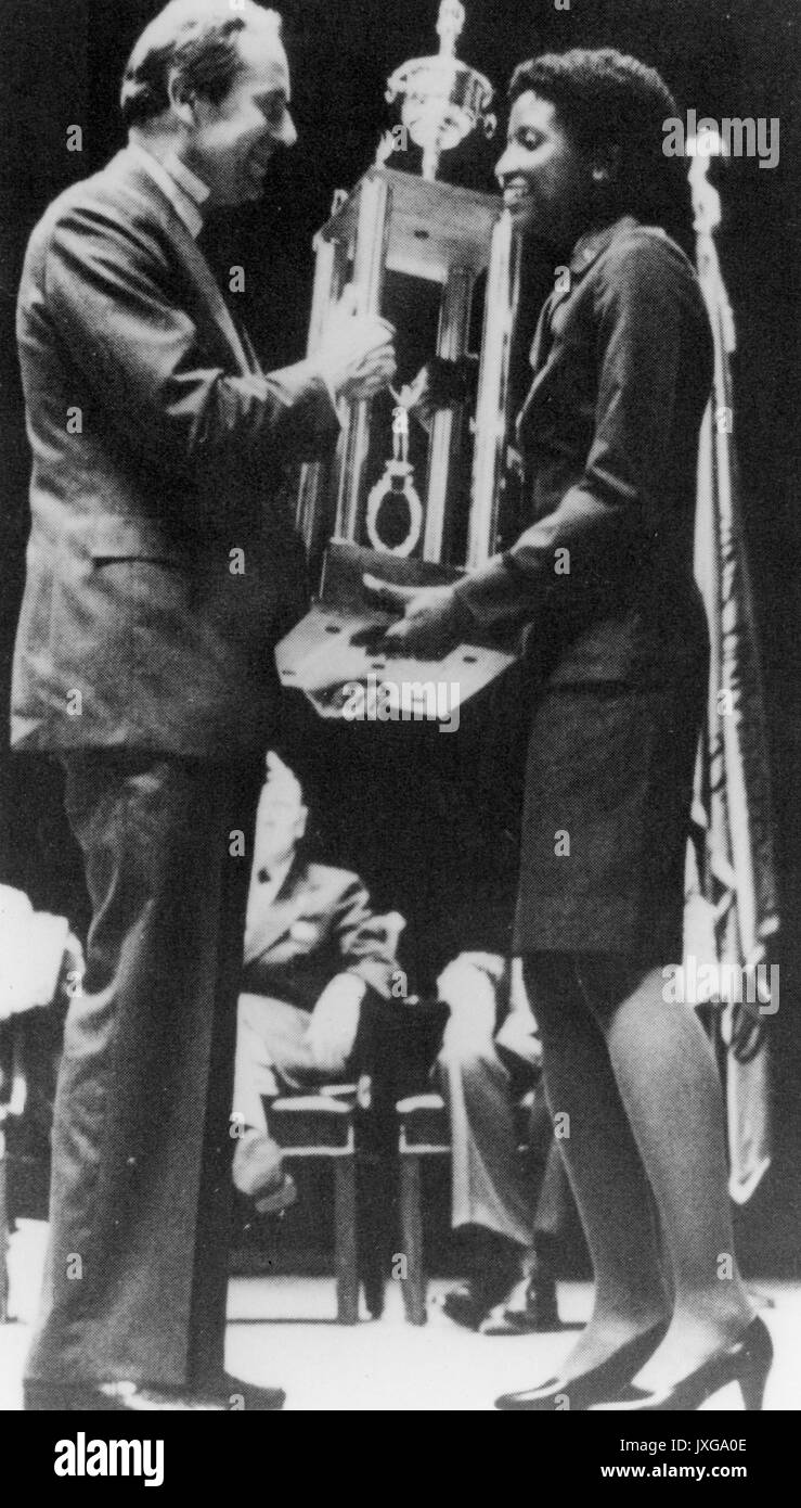 Man presenting a large trophy to an unidentified African-American woman, 1981. Stock Photo