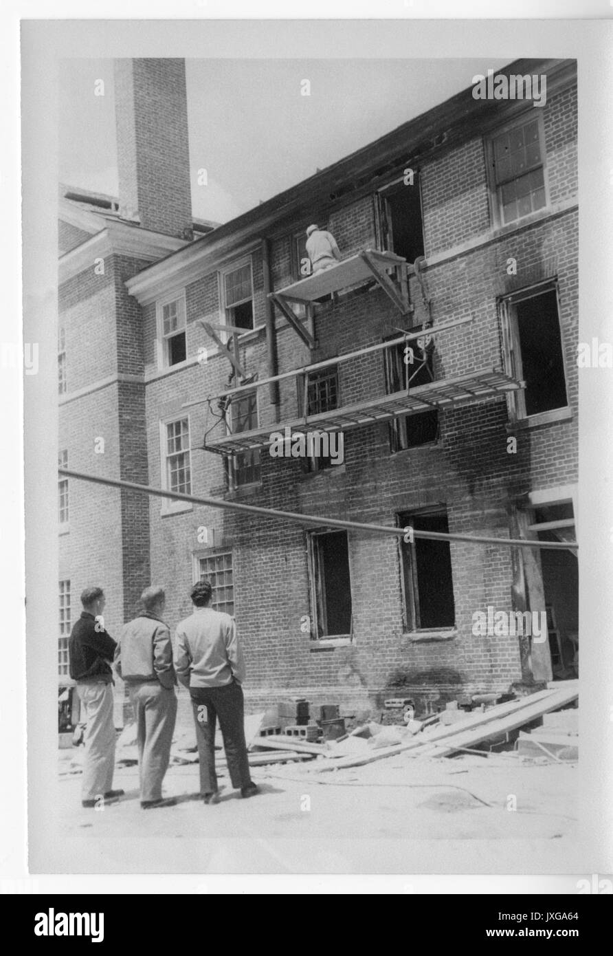 Alumni Memorial Residences, Dormitory Construction of second dormitory, Three students are looking at a man doing construction work on a scaffold, 1954. Stock Photo