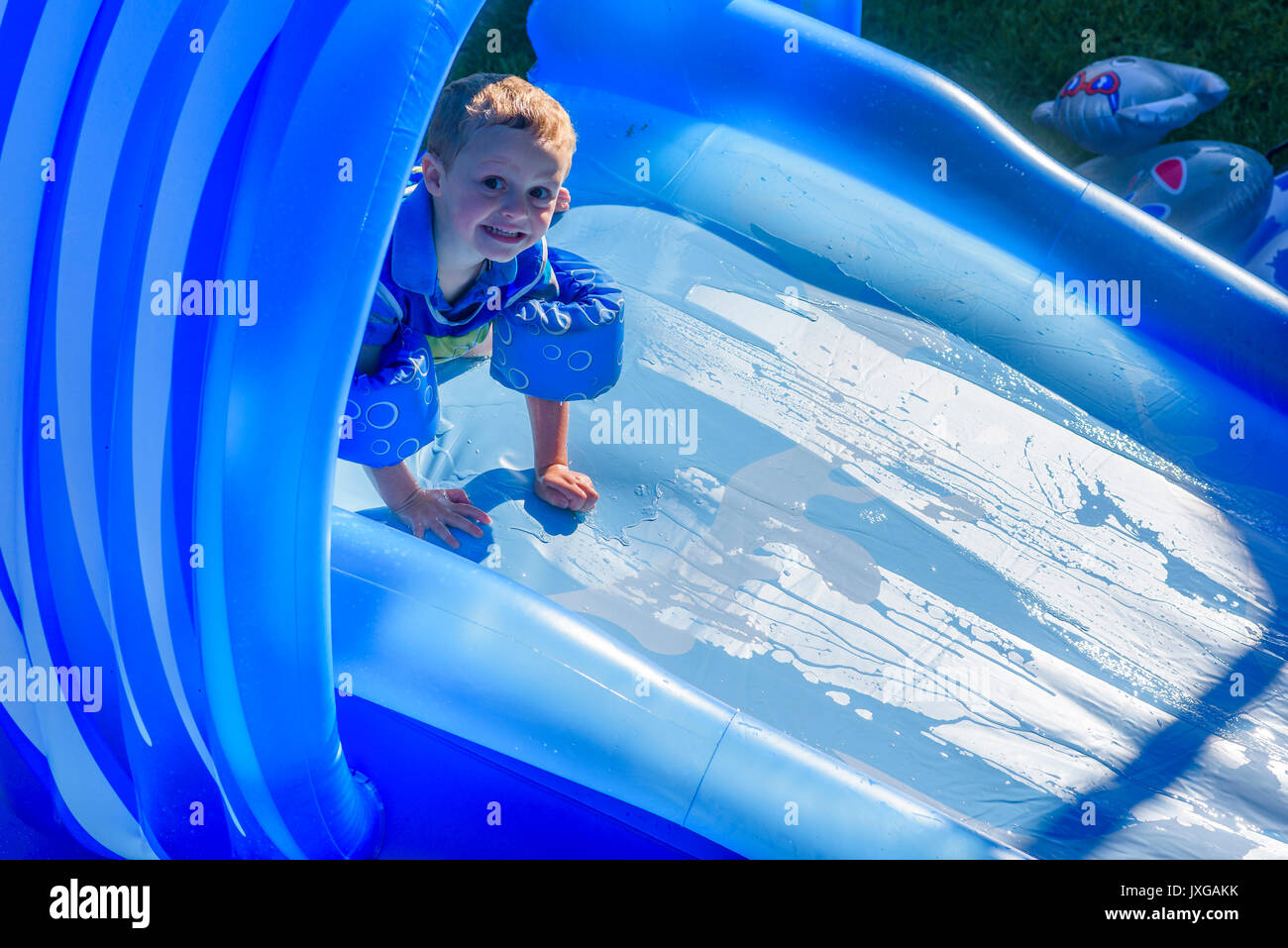 Young boy on backyard water slide. Stock Photo