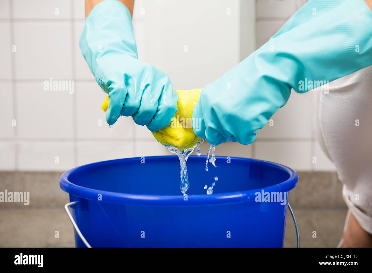 Close-up Of Cleaning Service Woman Hand Squeezing Cloth In Bucket At Home Stock Photo