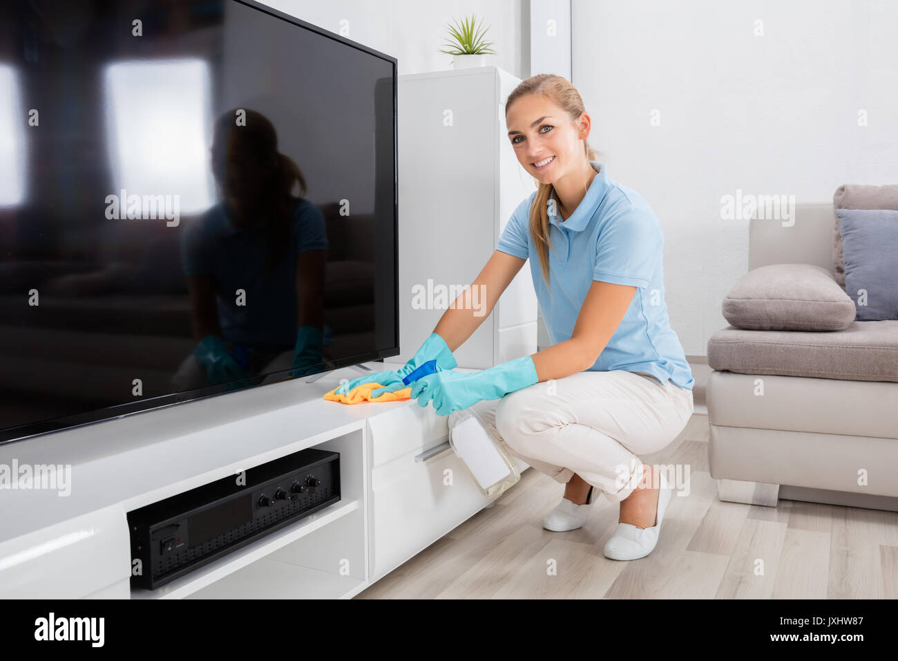 Young Happy Woman Cleaning The Furniture Of Living Room At Home Stock Photo