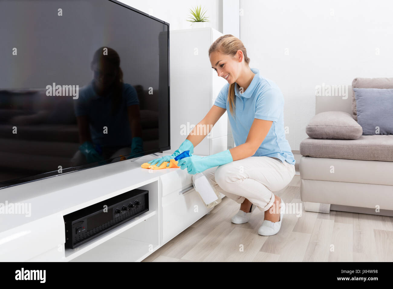 Young Happy Woman Cleaning The Furniture Of Living Room At Home Stock Photo