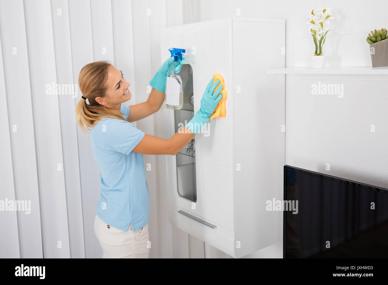 Young Smiling Woman Cleaning Furniture With Cleansing Product At Home Stock Photo