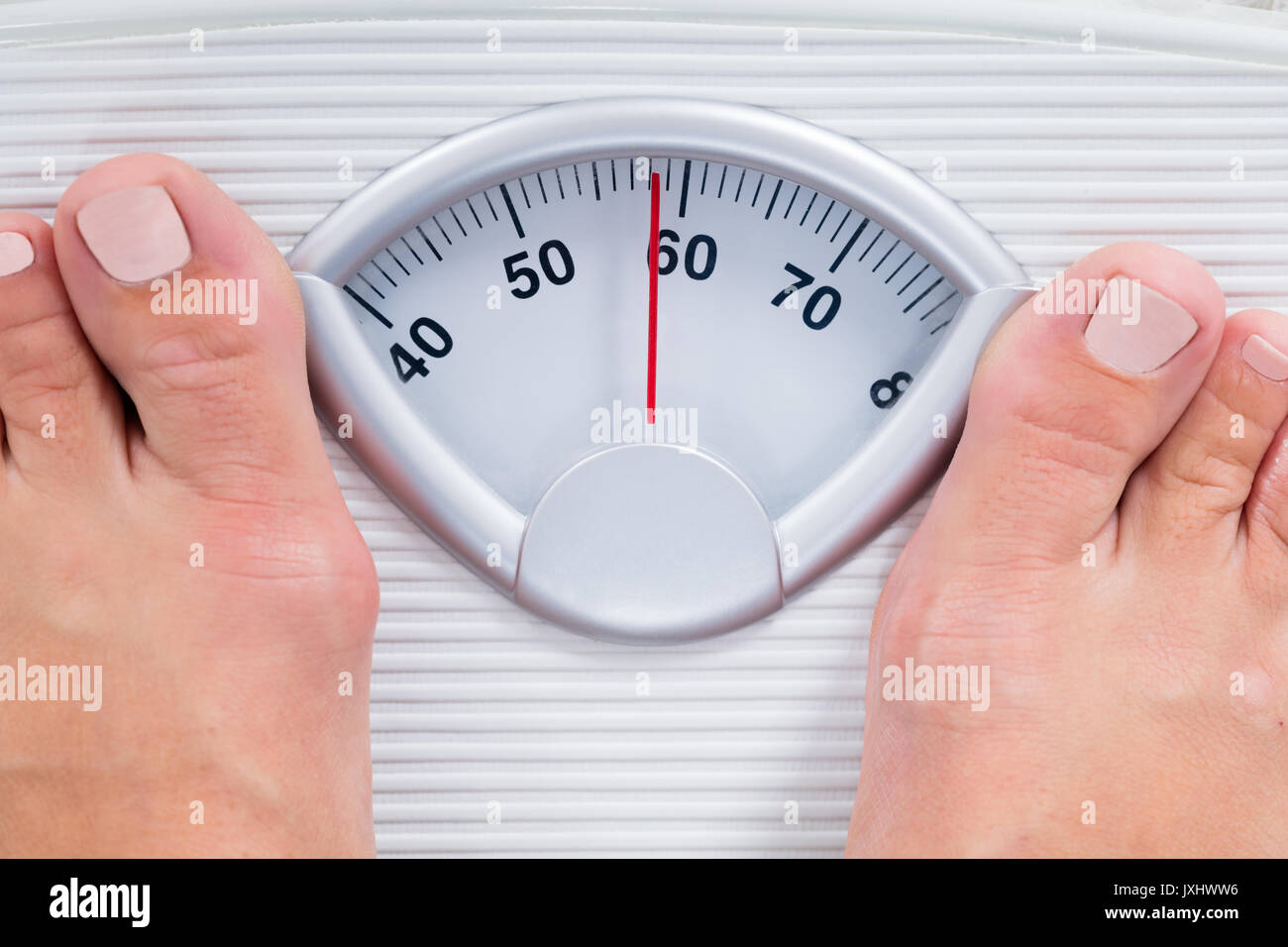 Close-up Of Person Feet Standing On Weighing Scale Stock Photo
