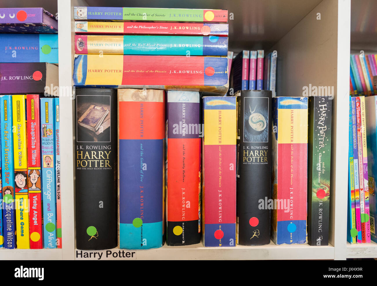 Some of J.K. Rowling's Harry Potter titles sitting on a bookshelf in a second-hand bookshop Stock Photo