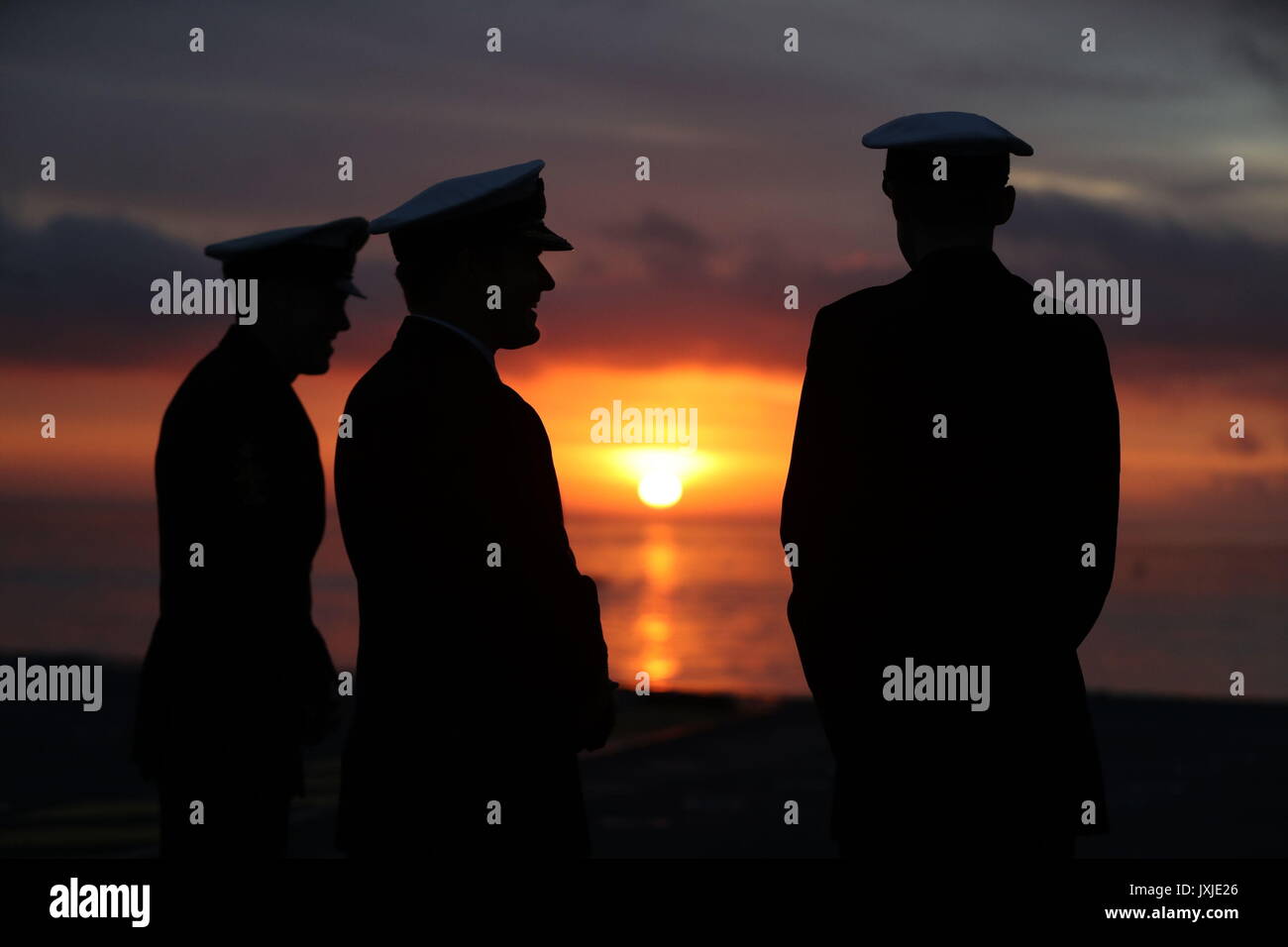 Members of the crew of HMS Queen Elizabeth, the UK's newest aircraft carrier, stand on the deck at sunrise ahead of the ship's arrival in Portsmouth. Stock Photo