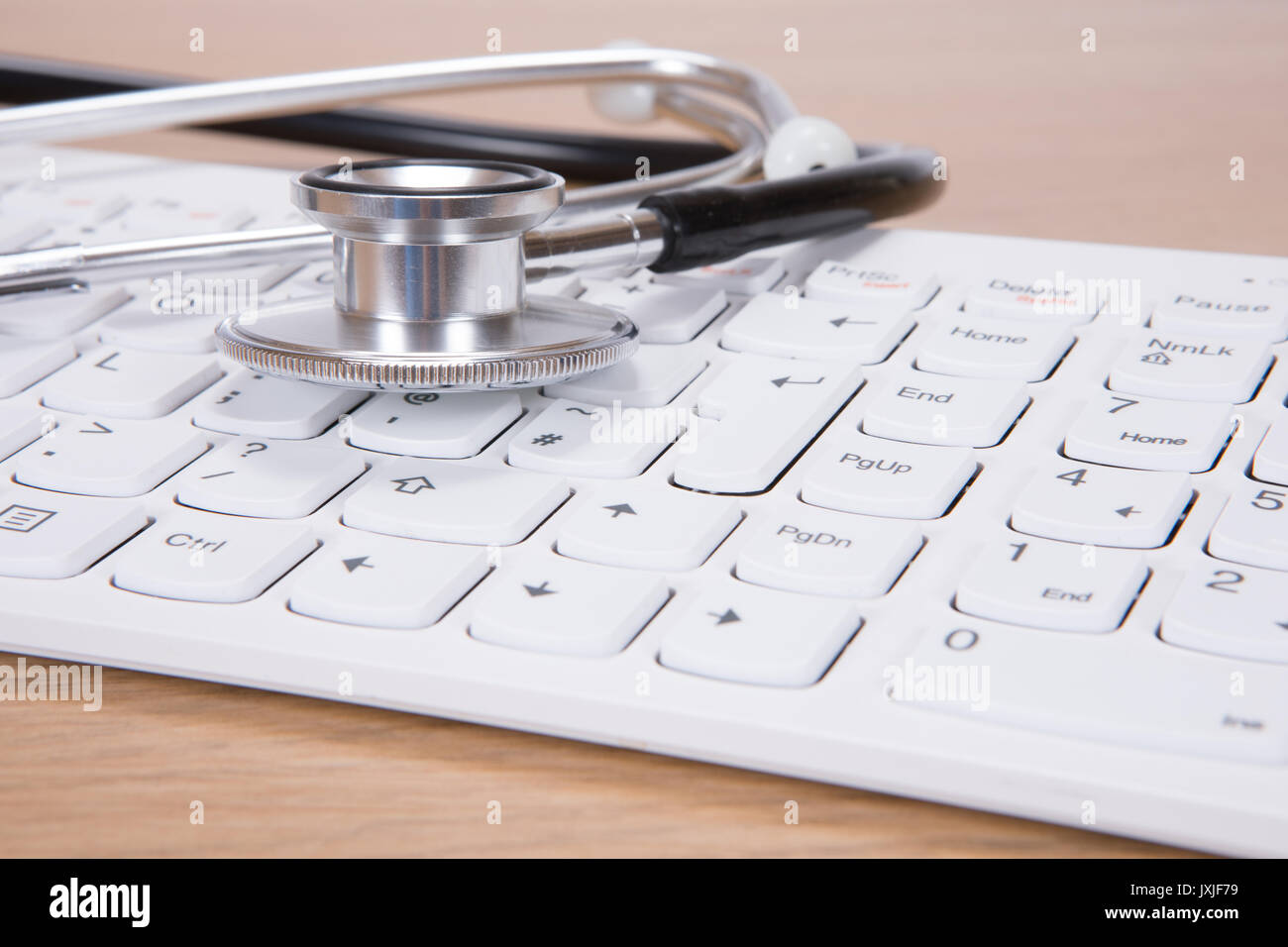 Close-up of acoustic stethoscope lying on computer keyboard Stock Photo