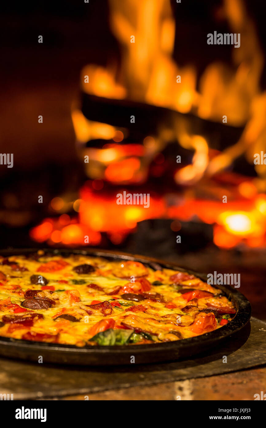 Wood fired pizza oven pizza with fire in background and shallow depth of field Stock Photo