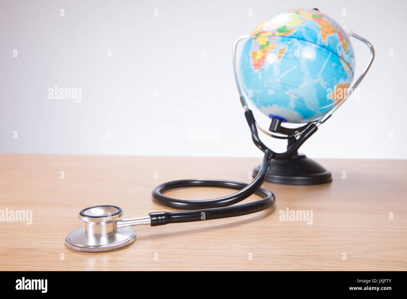 Small miniature toy plastic globe with stethoscope attached Stock Photo