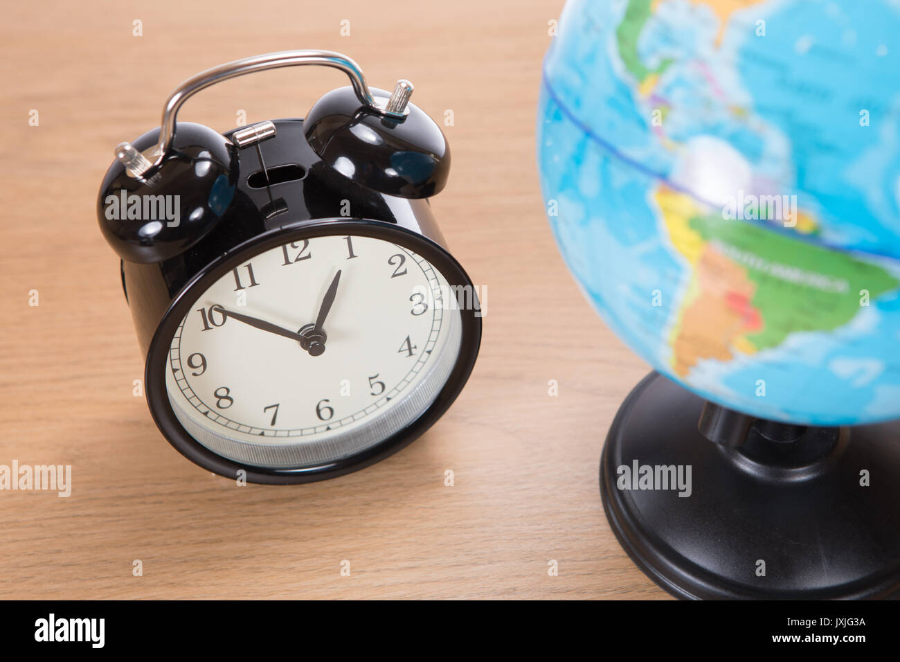 Retro oldfashioned bell alarm clock alongside a world globe in a