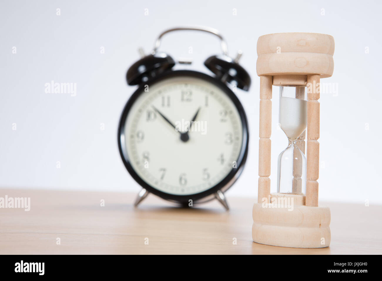 Small wooden egg timer with an alarm clock on a wooden table with focus