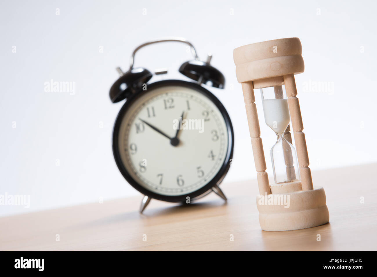 Tilted angle view of a wooden egg timer or hourglass with a retro alarm