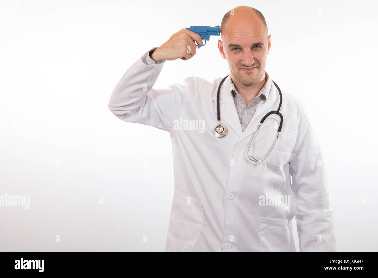 Suicidal doctor under stress from overwork holding a toy plastic gun to his head in a conceptual image Stock Photo