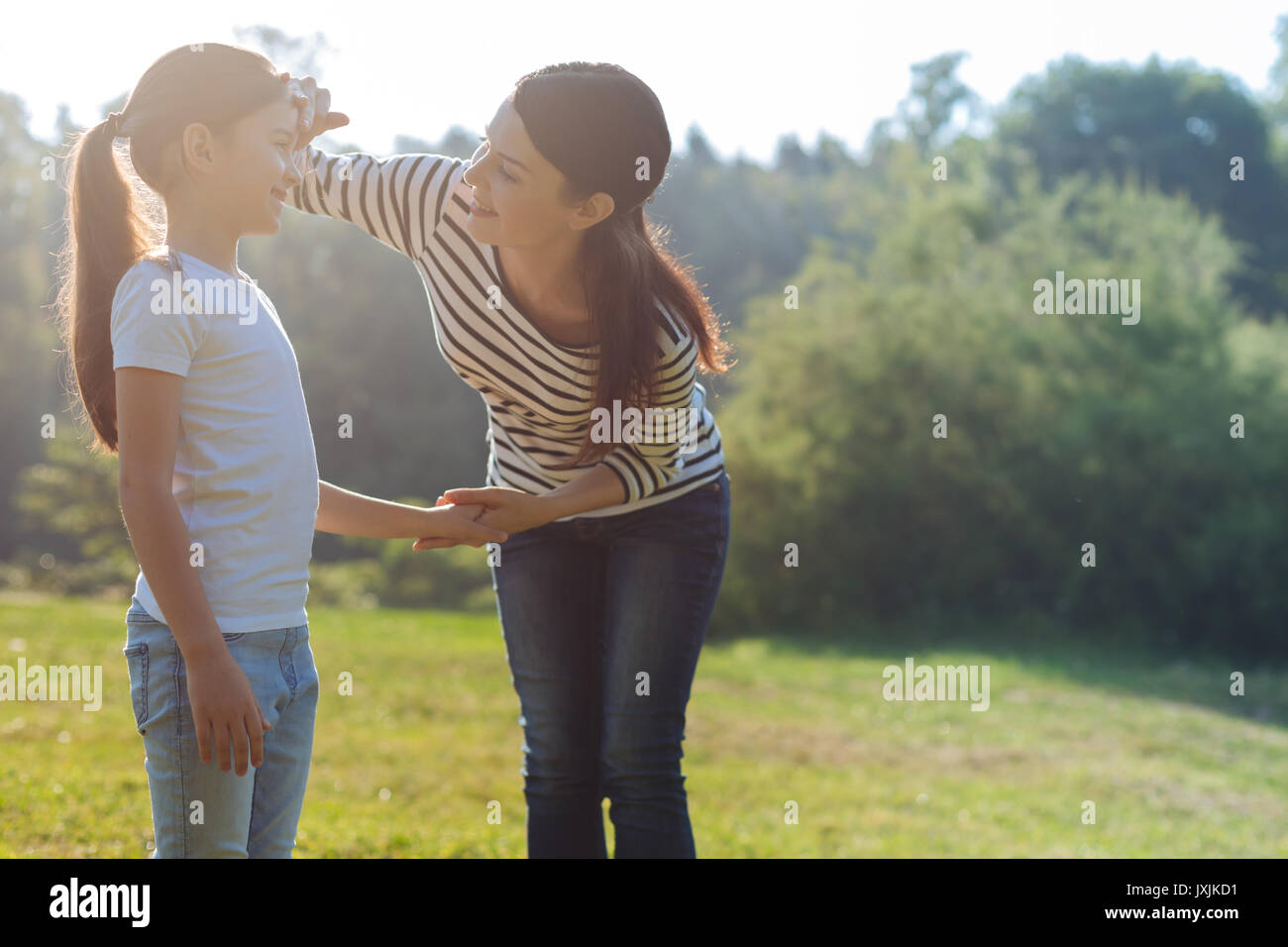 Loving mother gently touching her daughters forehead Stock Photo