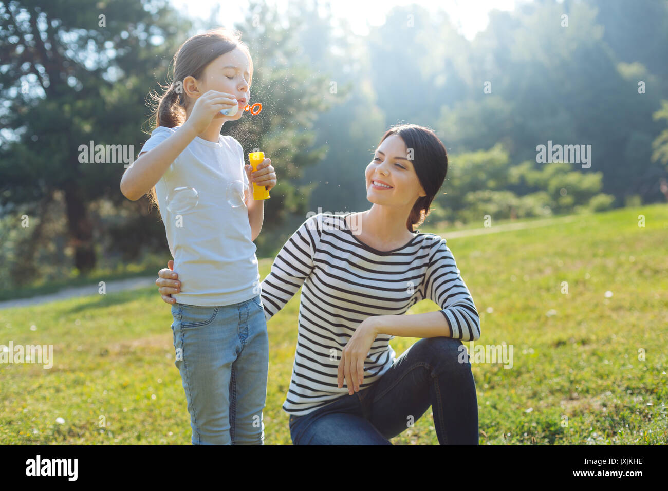 Charming mother watching her daughter blow bubbles Stock Photo