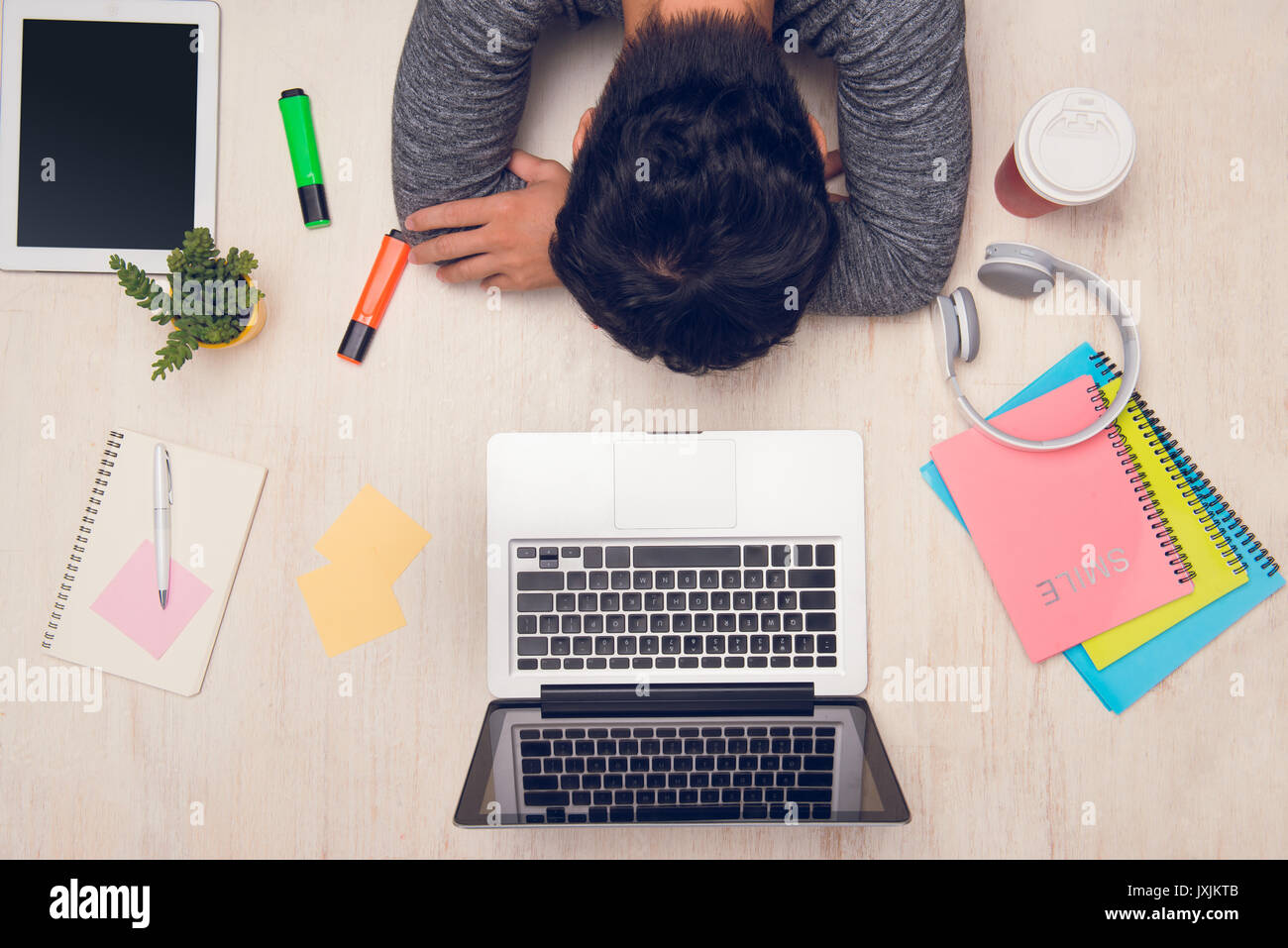 Student guy sleeping on desk with books around. Top view Stock Photo