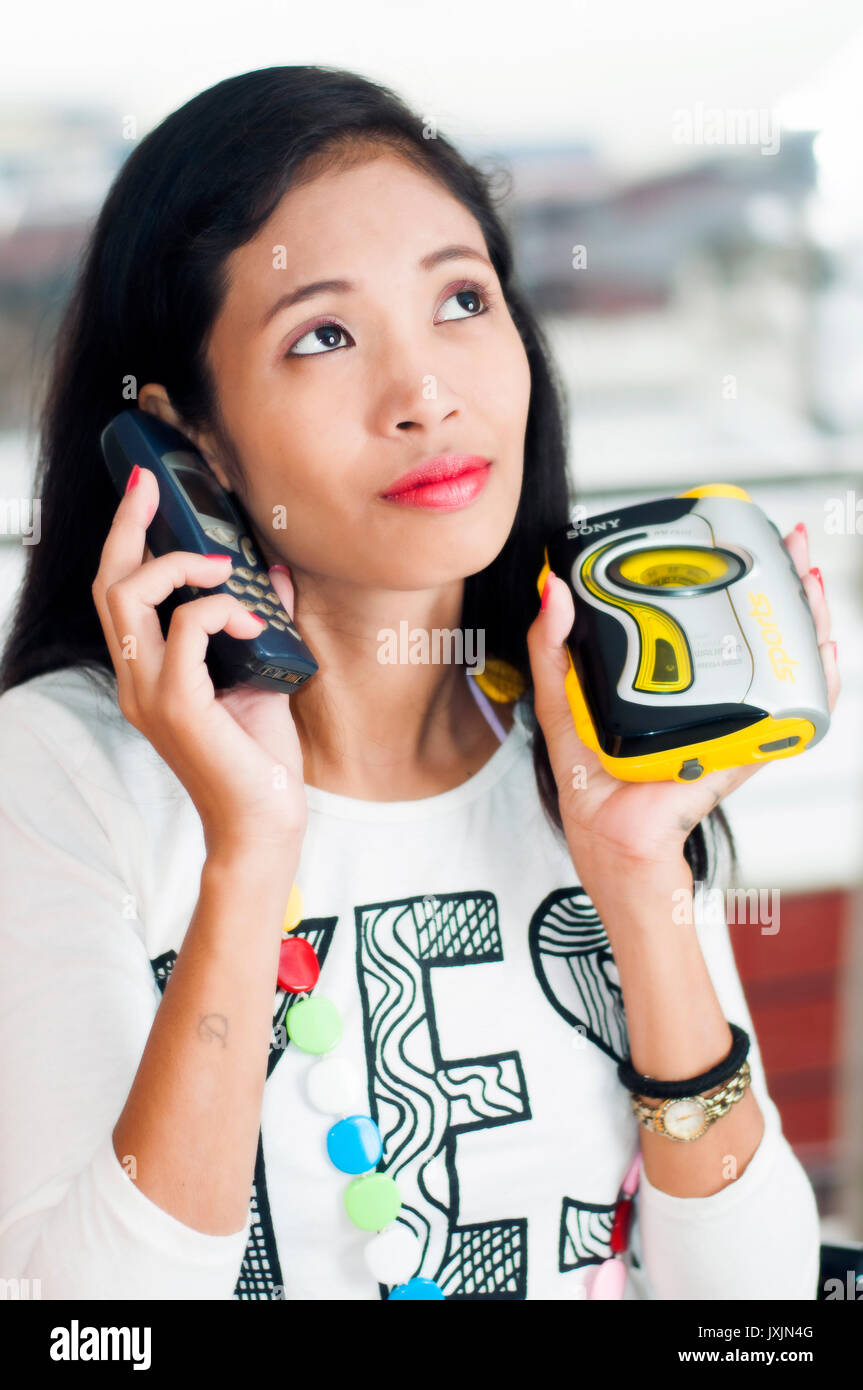 Young Asian woman holding retro Nokia phone and walkman sports Stock Photo