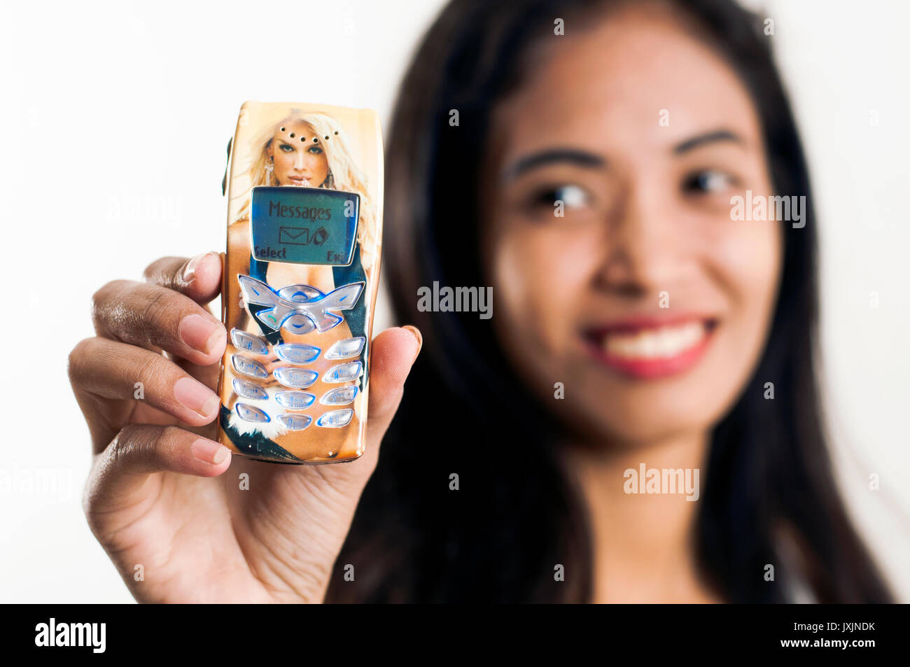 Young Asian woman holding retro Nokia 8250 cell phone in studio setting Stock Photo
