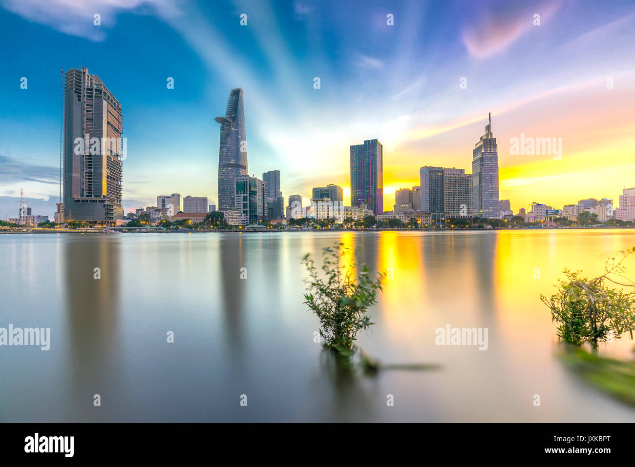 Ho Chi Minh City, Vietnam - June 15th, 2017: Riverside City sunrays clouds in the sky at end of day brighter coal sparkling skyscrapers along beautifu Stock Photo