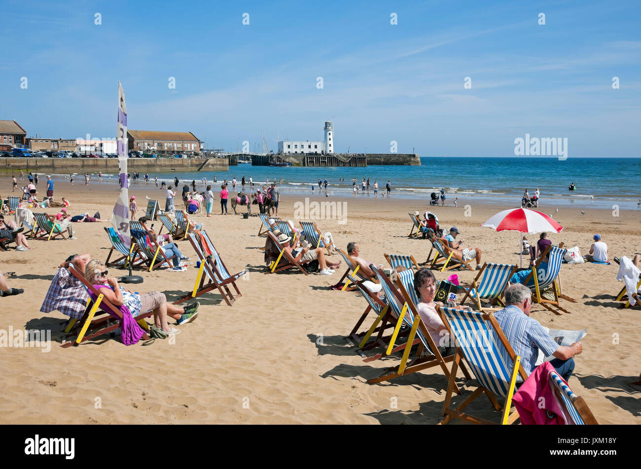 People visitors tourists on deckchairs South Bay beach in summer Scarborough seafront North Yorkshire England UK United Kingdom GB Great Britain Stock Photo