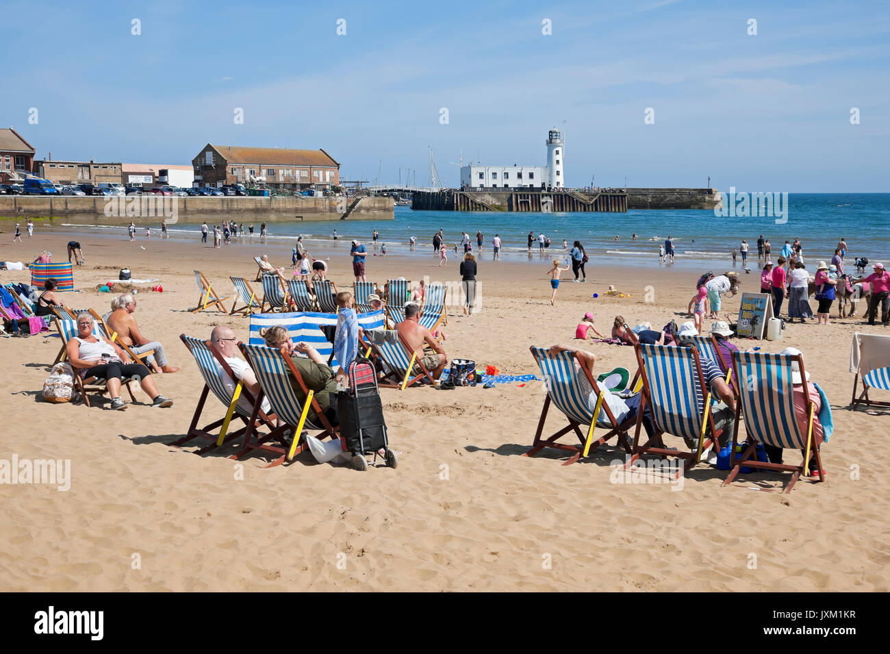 People visitors tourists sat on deckchairs on South Bay beach in summer Scarborough North Yorkshire England UK United Kingdom GB Great Britain Stock Photo