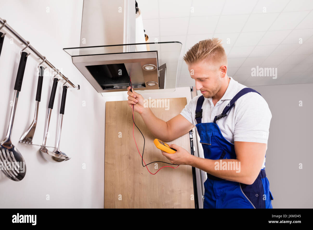 Young Male Technician Checking Kitchen Extractor Filter With Digital Multimeter Stock Photo