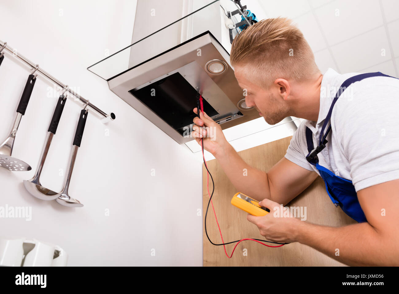 Young Male Technician Checking Kitchen Extractor Filter With Digital Multimeter Stock Photo