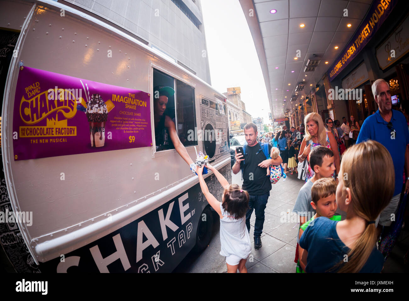 Theatre-goers exiting the Lunt-Fontanne Theatre on Broadway in New York on Wednesday, August 9, 2017 excitedly buy an 'Imagination Shake' from the Shake by Black Tap milkshake truck. The collaboration between the Roald Dahl 'Charlie and the Chocolate Factory' musical and and the Black Tap is an over-sized shake with purple and gold rock candies, whipped cream, chocolate chips, chocolate drizzle topped with a chocolate'golden ticket' as in the musical. Perfect for an after matinee indulgent. The truck will appear after matinees through September. (© Richard B. Levine) Stock Photo